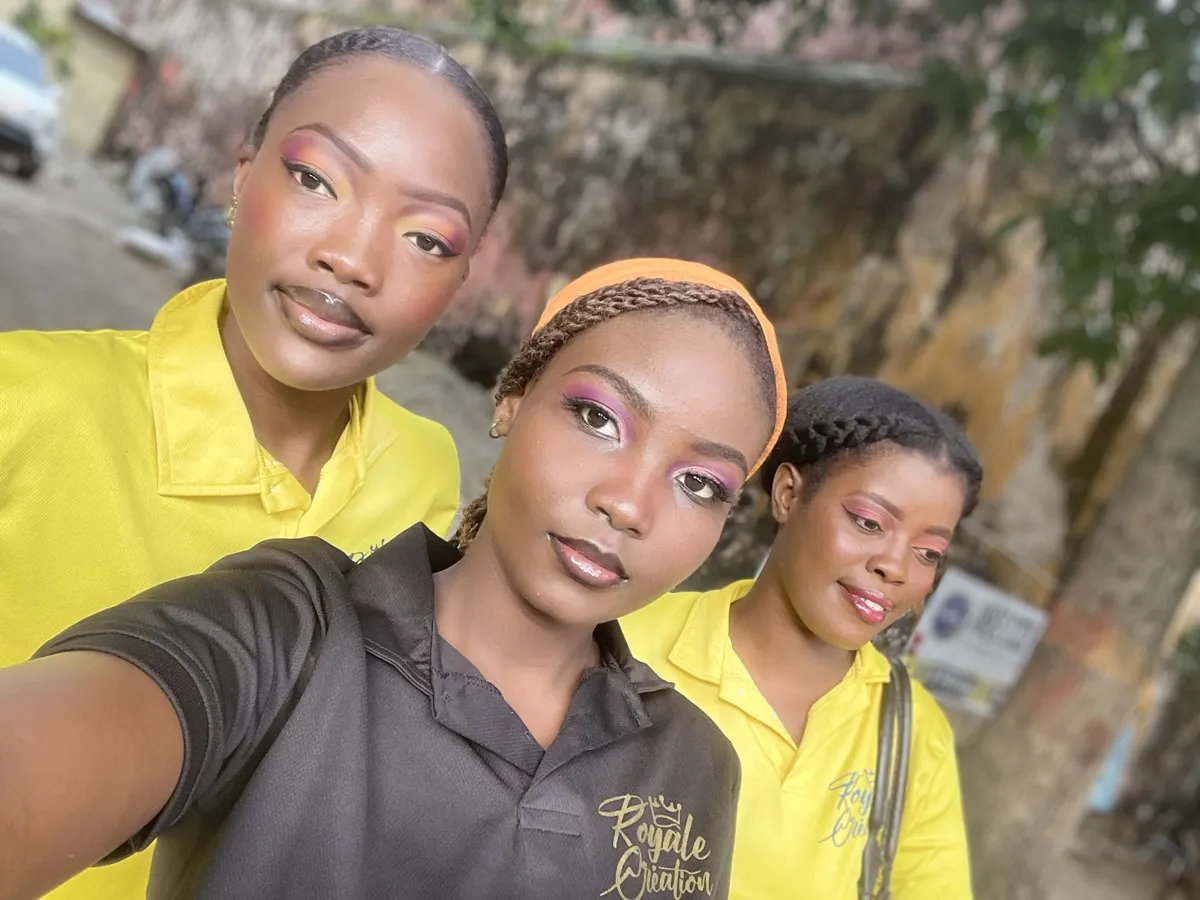 Trois étudiantes de Royale Création présentant un maquillage coloré, en polos jaunes et noir